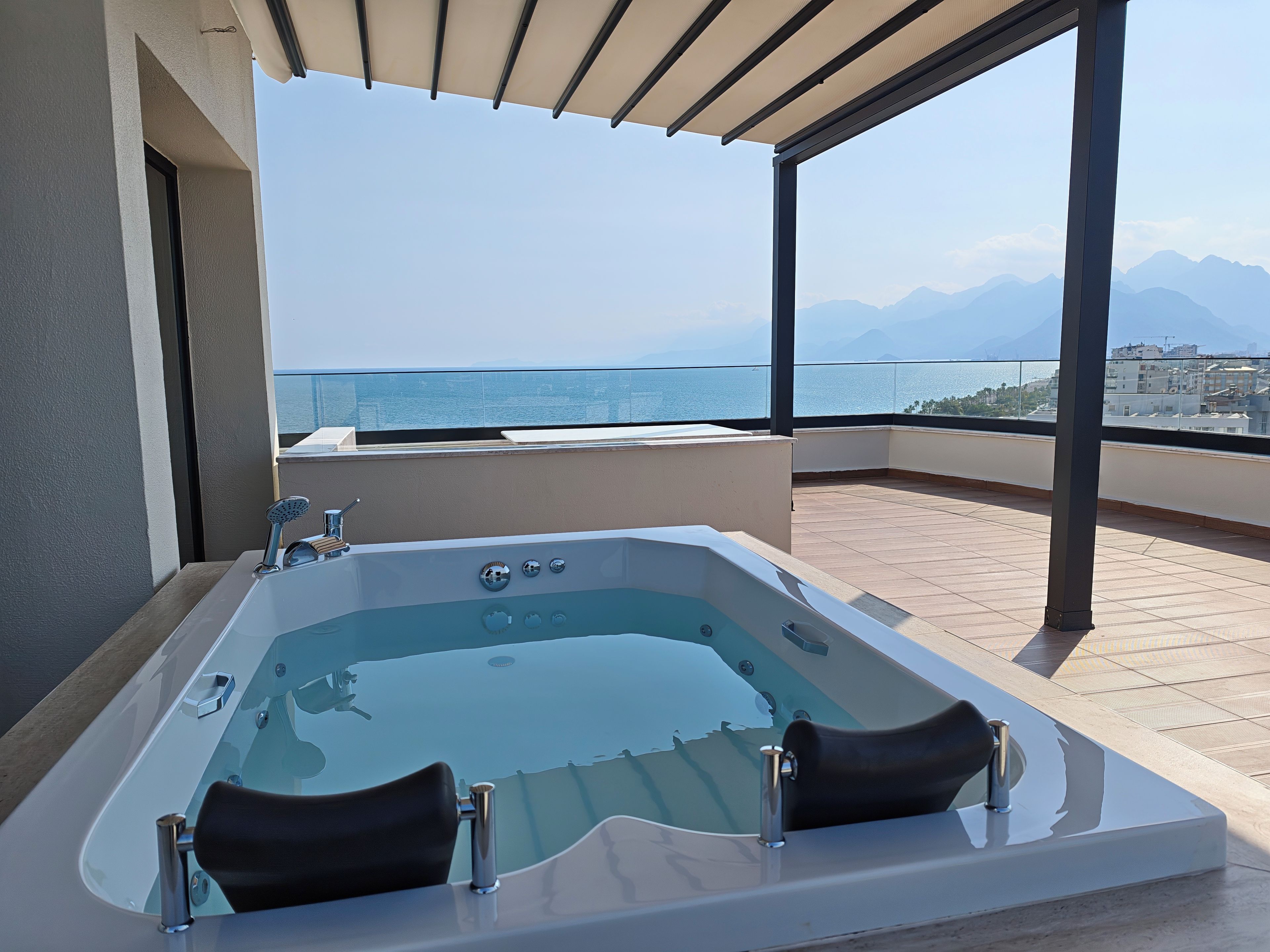 Ein moderner Whirlpool im Freien mit freiem Blick auf das Meer und die Berge.