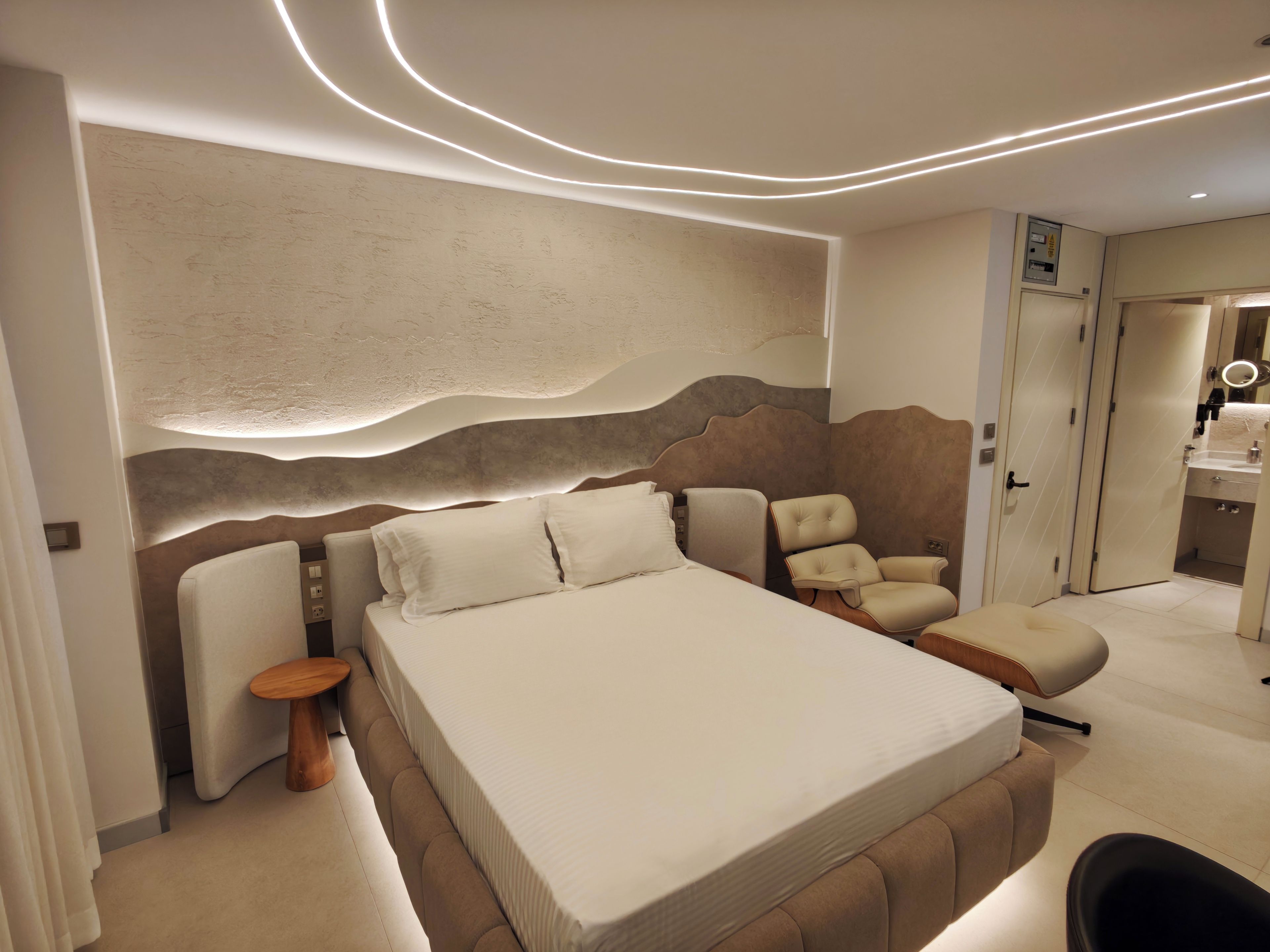Un dormitorio moderno con una cama grande, una zona de estar y un baño.