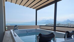 A modern outdoor hot tub with a city view, large windows, and a clear sky.