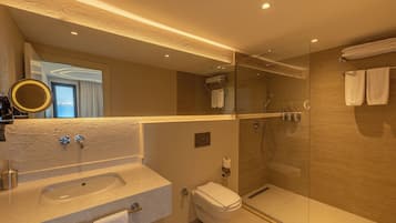 Un baño moderno con ducha envuelta en vidrio, lavamanos con espejo e inodoro.