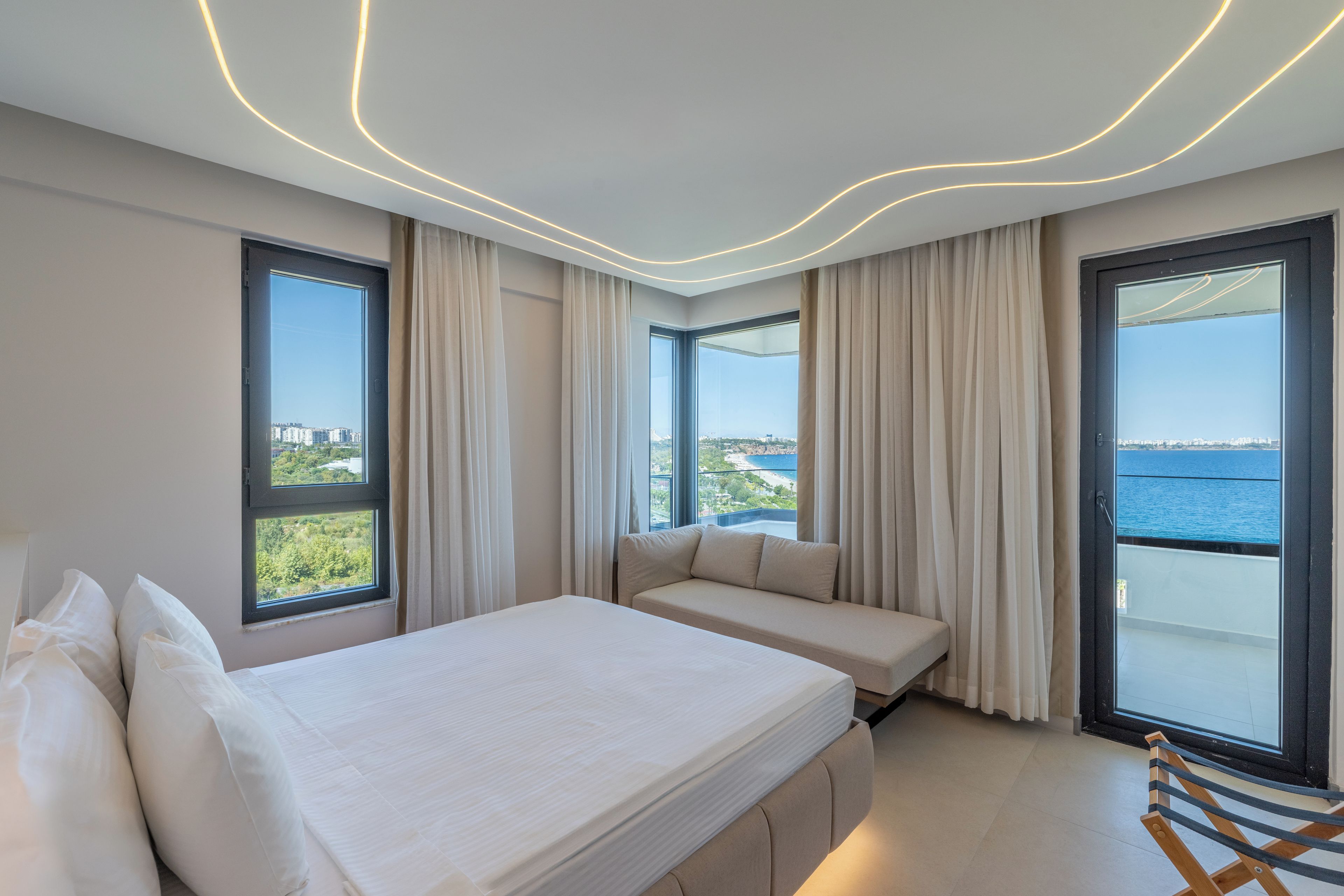 Un dormitorio moderno con una cama grande, un sofá cama y vista al mar.