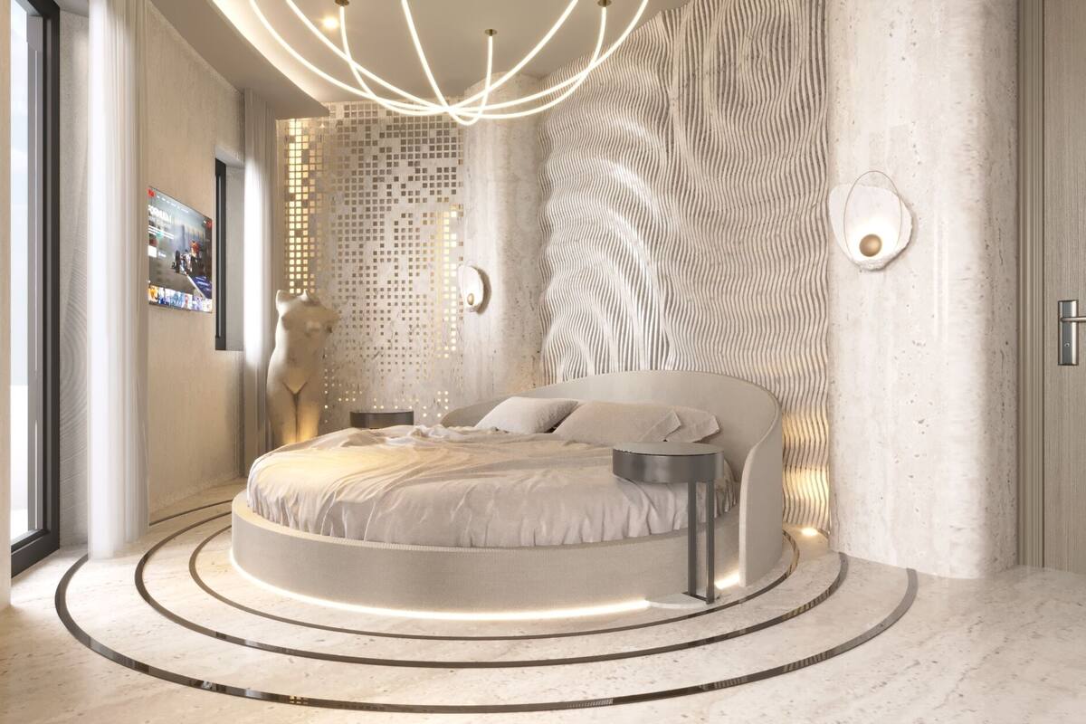 A circular bed with a modern design, a wall-mounted TV, and a unique textured wall.