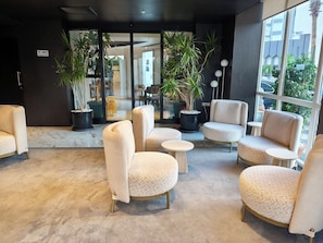 A modern interior with seating, potted plants, and a view through glass doors. - The Corner Park Hotel (Konyaalti)
