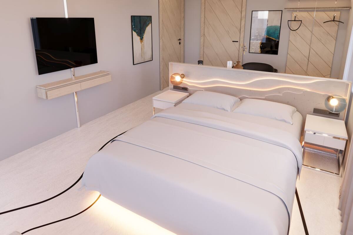 A modern bedroom with a bed, bedside tables, a TV, and a mirror.