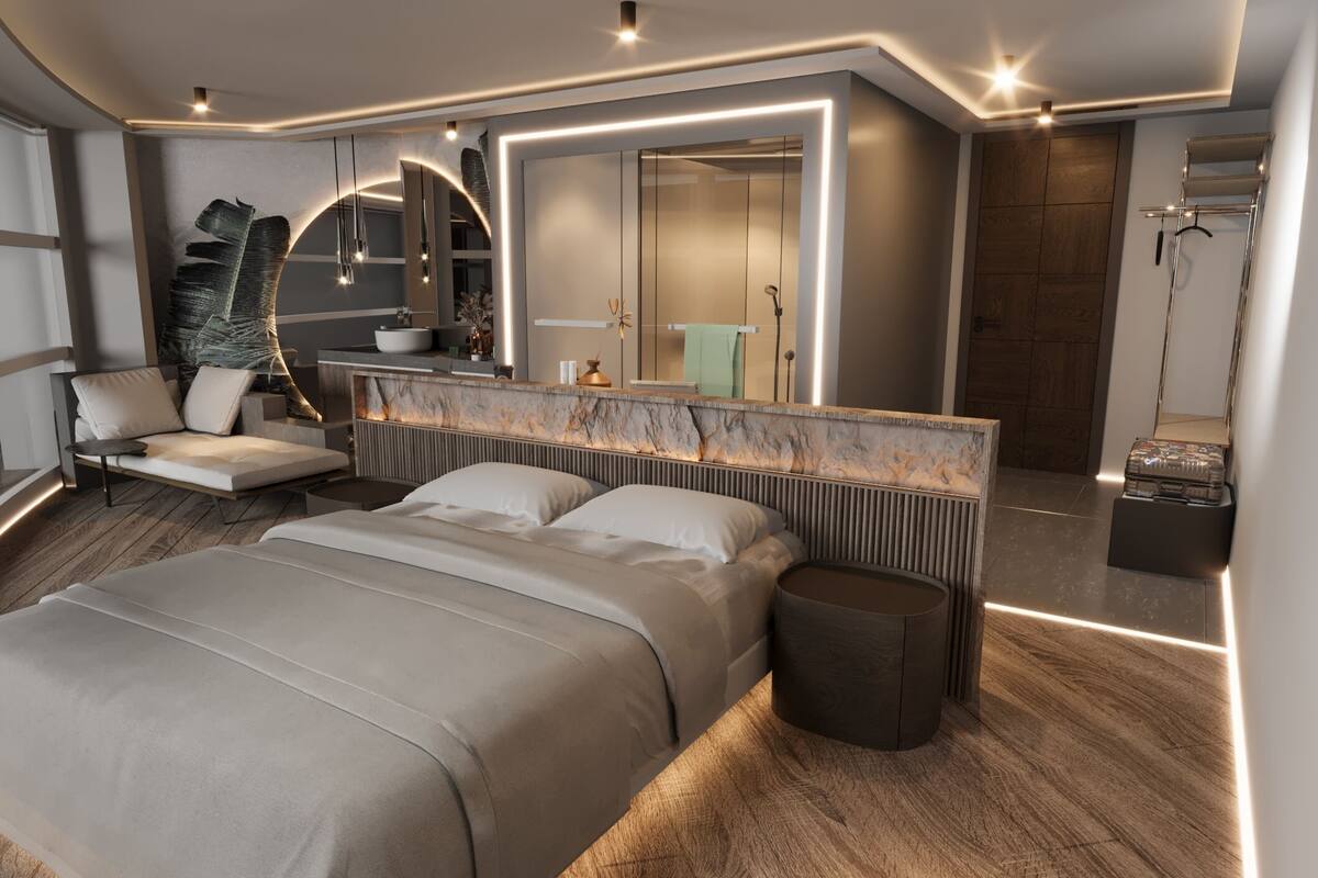 A modern bedroom with a large bed, a seating area, a vanity, and a mirror.