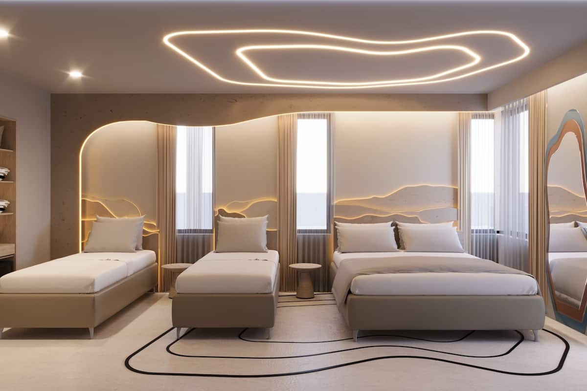 A modern hotel room with two beds, a small round table, and a large mirror.