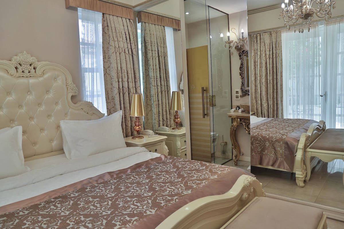 Une chambre à coucher luxueuse, dotée d’un grand lit, d’une coiffeuse avec un miroir et d’un lustre.