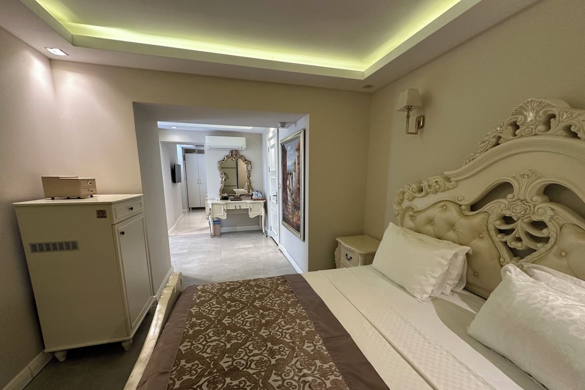 Une chambre d’hôtel avec un grand lit, une commode, une coiffeuse avec un miroir et un tableau au mur.