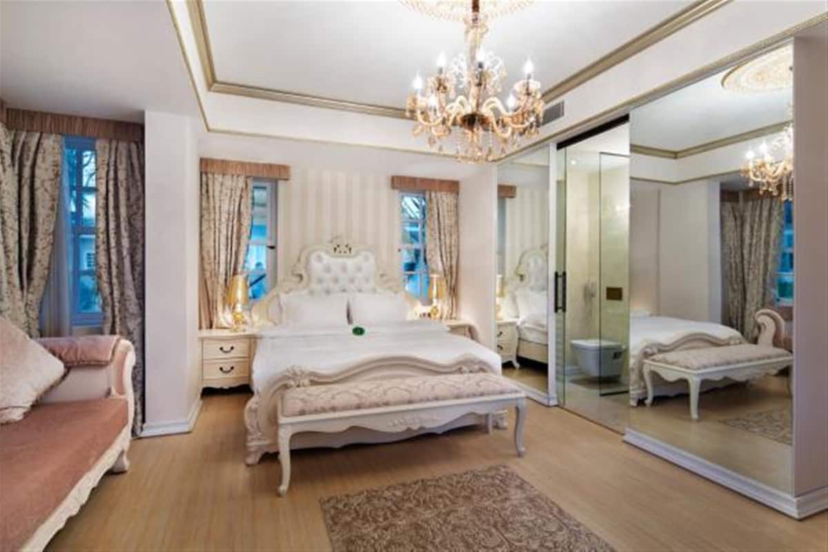 Une chambre à coucher luxueuse avec un grand lit, un coin salon et un placard avec des portes miroir.