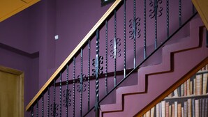 Una escalera con una pared morada y una estantería llena de libros.