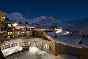 A snow-covered resort with multiple buildings, a ski lift, and a mountain backdrop.