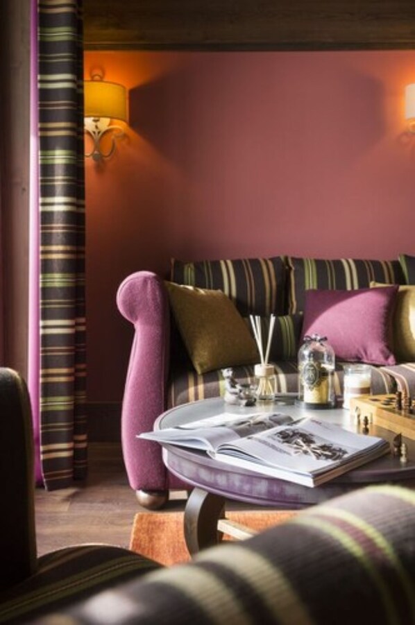 A cozy room with a striped sofa, a small table with a magazine, and a lamp.