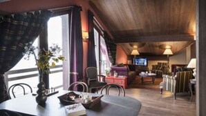 Una sala de estar acogedora con techo de madera, un televisor y un área de descanso con sofá y sillones.