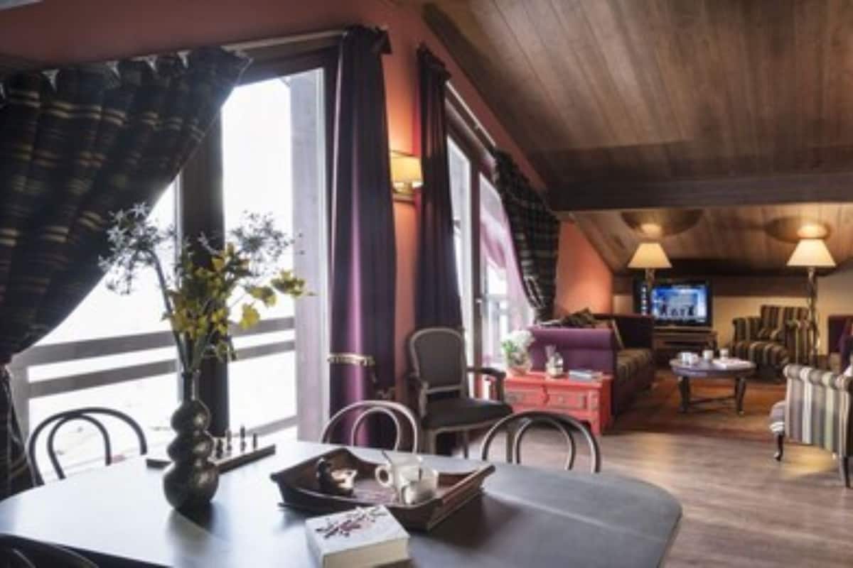 A cozy living room with a wooden ceiling, a television, and a seating area with a sofa and chairs.