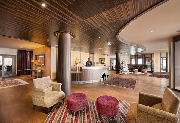 A spacious lobby with a reception desk, plush seating, and a Christmas tree.