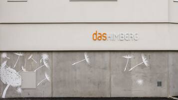 Fachada de edifício com o nome 'das HIMBERG' em letras laranja.