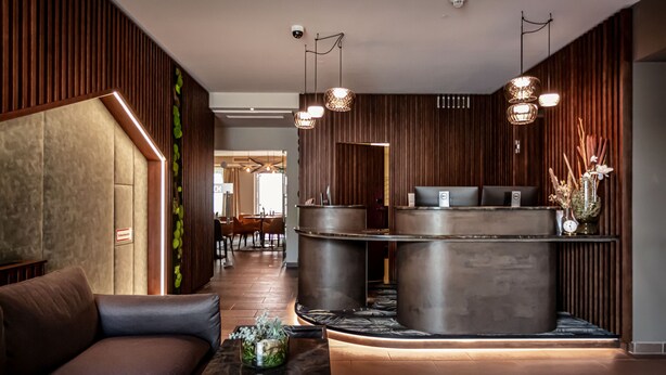 Un área de recepción moderna con un mostrador de madera, asientos de cuero e iluminación ambiental.