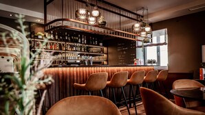 Una zona de bar con una variedad de botellas y copas, un menú en la pizarra y varias sillas.