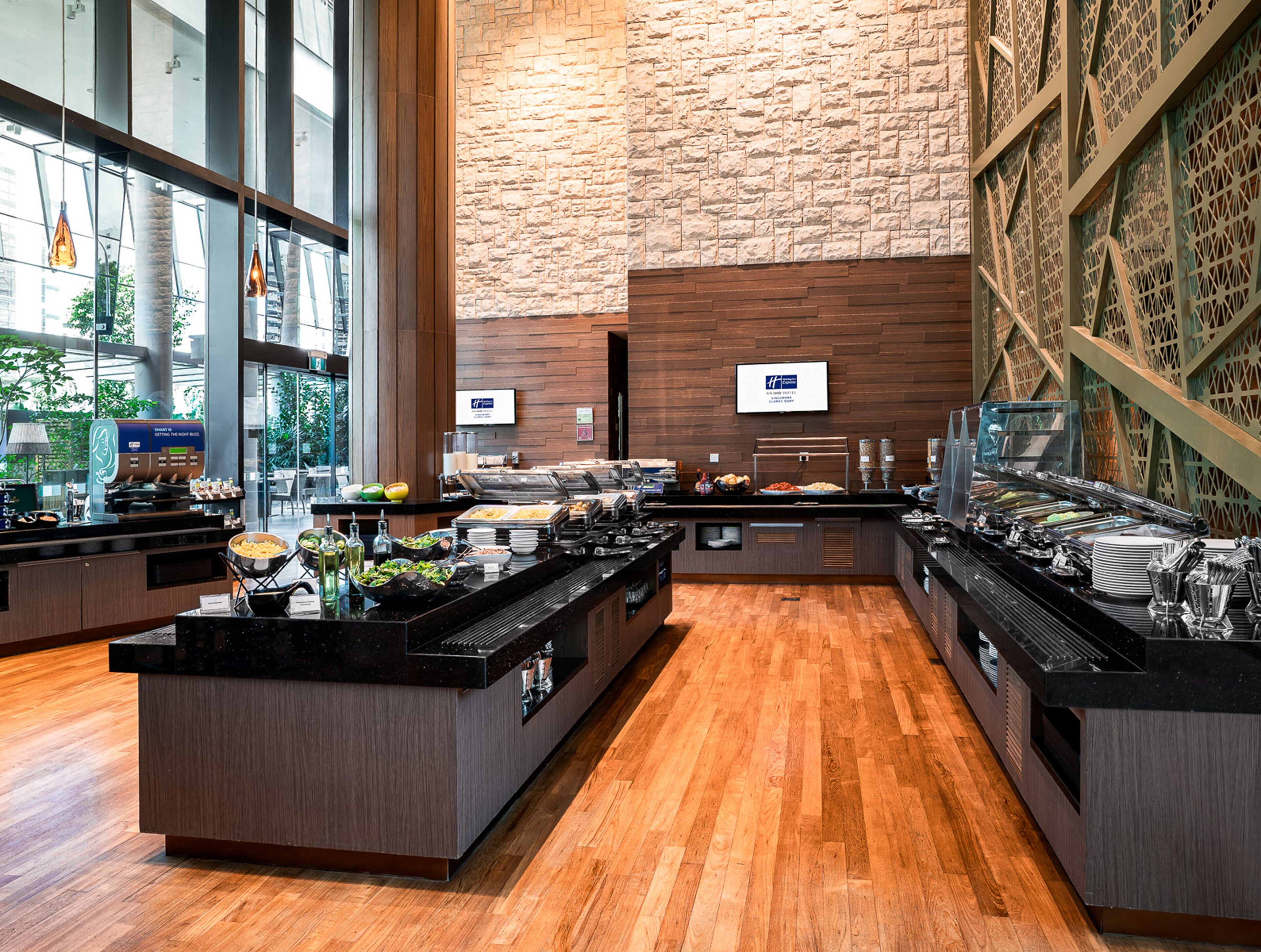 A buffet area with multiple serving stations, a stone wall, and a view of the outdoors.