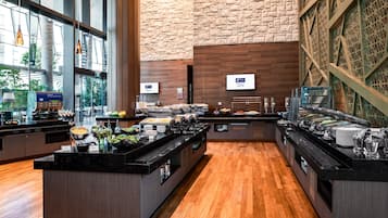 A buffet area with multiple serving stations, a stone wall, and a view of the outdoors.