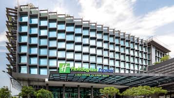 Experience the sleek, modern design of this hotel, featuring a grid-like facade with numerous windows and a covered entrance.