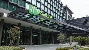 The exterior of the Holiday Inn Express Singapore Clarke Quay building with a modern glass facade and a green sign.