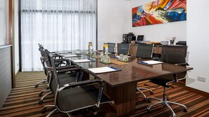 Un salón de conferencias con una larga mesa, sillas y una estación de café.
