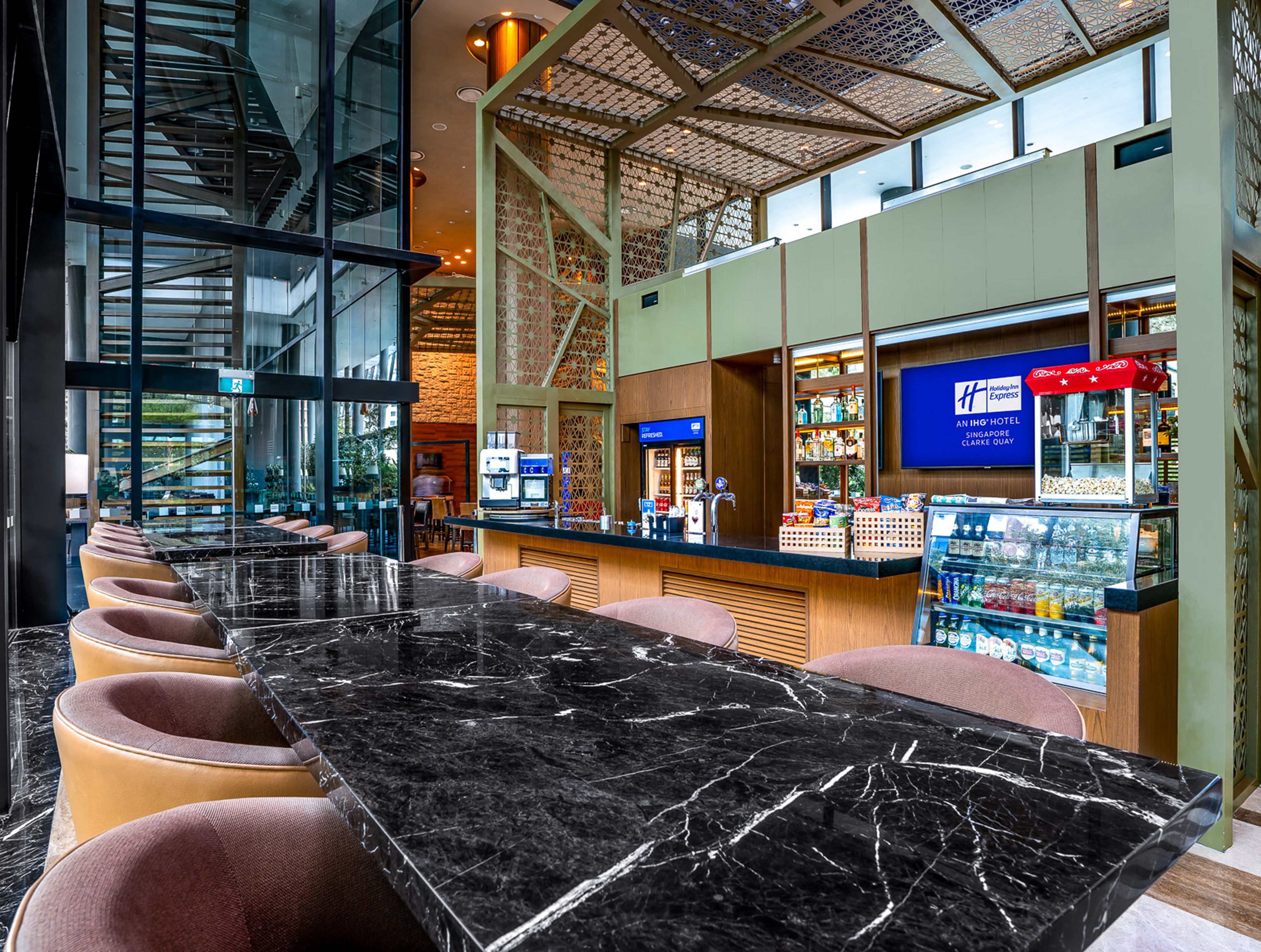 A hotel lobby with a marble reception desk, seating area, and a view of the cityscape through large windows.