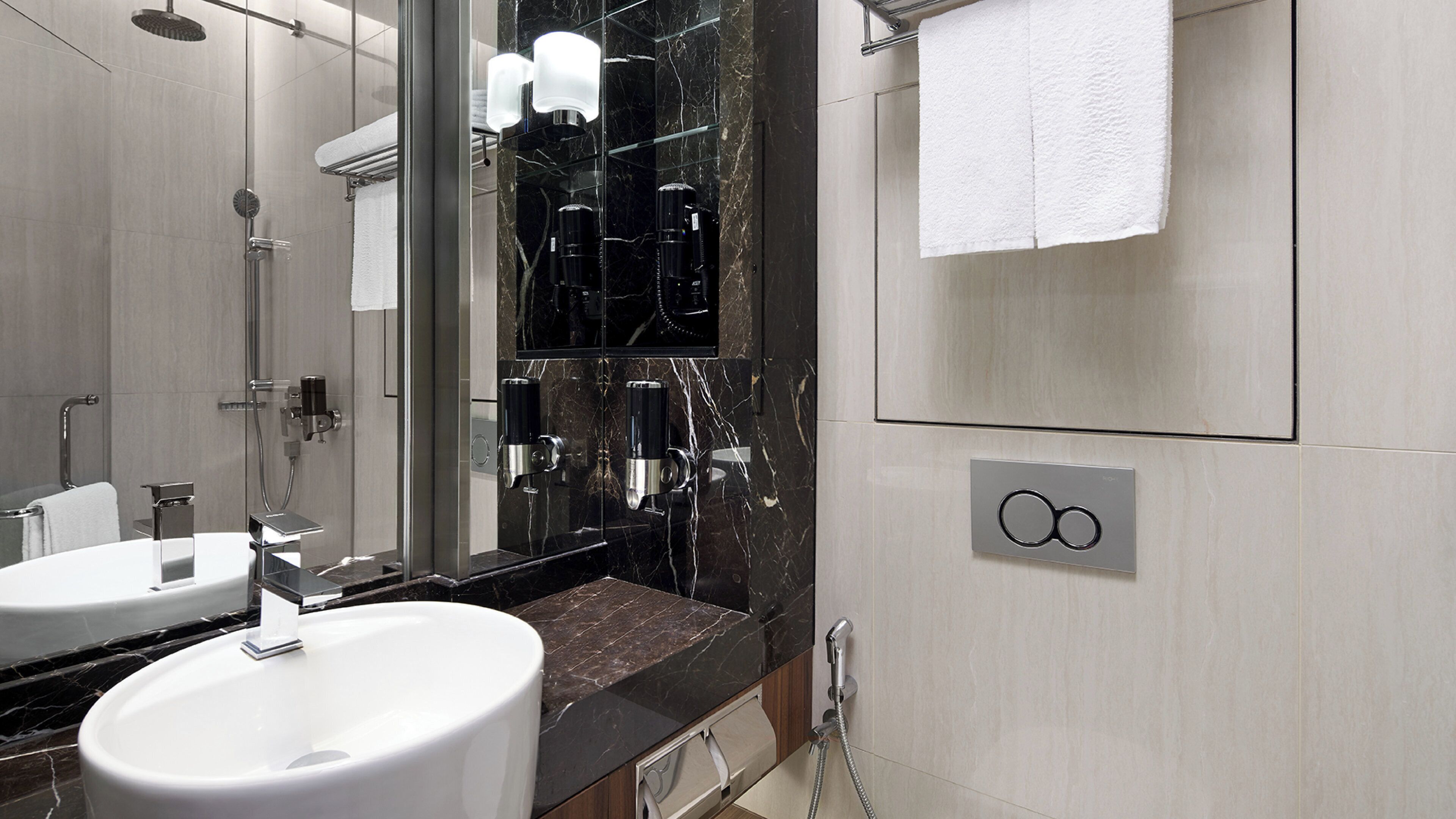 Ein modernes Badezimmer mit zwei Waschbecken, einer Dusche und einem Handtuchhalter.
