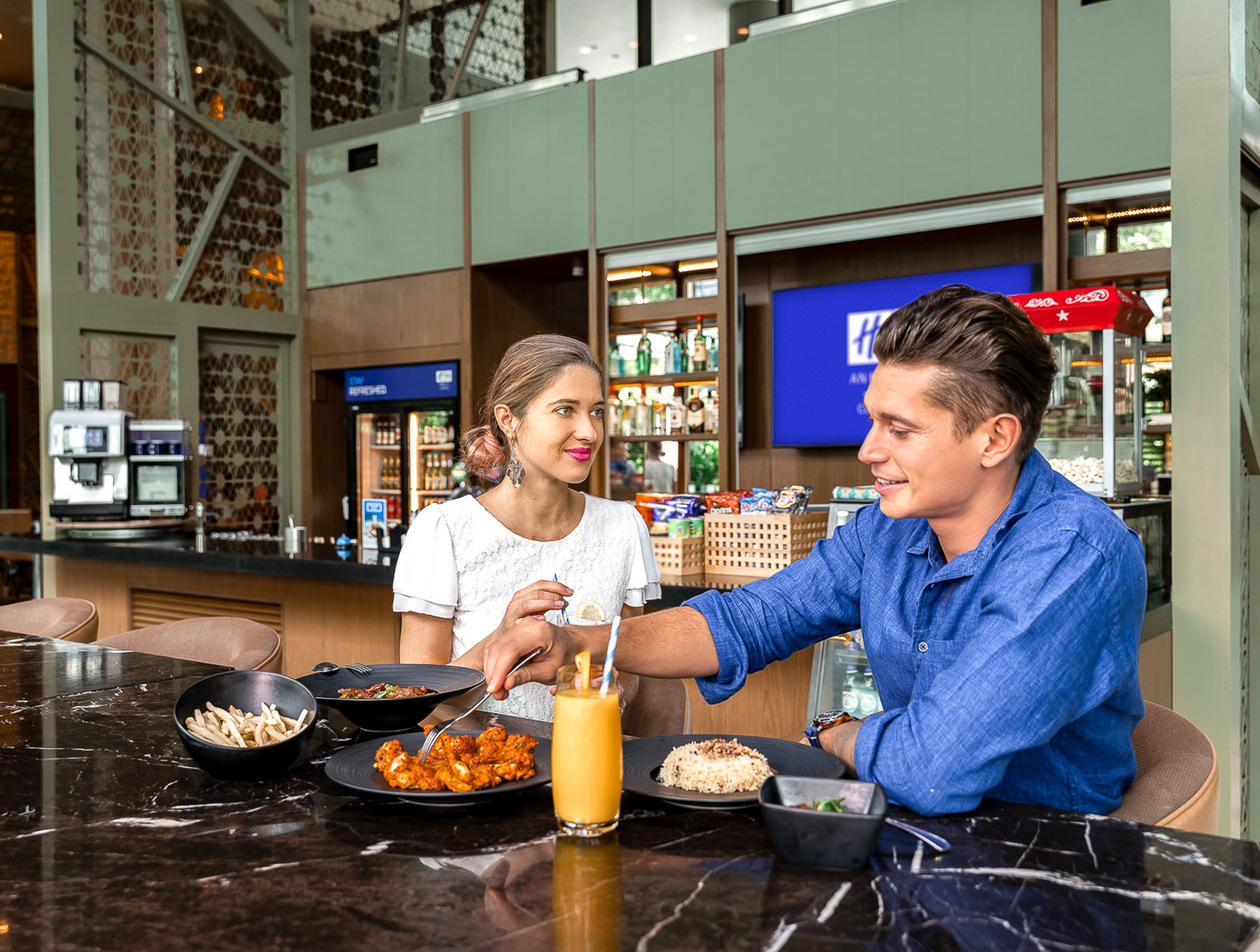 A restaurant setting with a bar area, seating, and a counter with food and drinks.