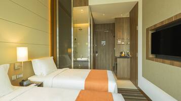 A hotel room with two beds, a TV, a bathroom, and a minibar.