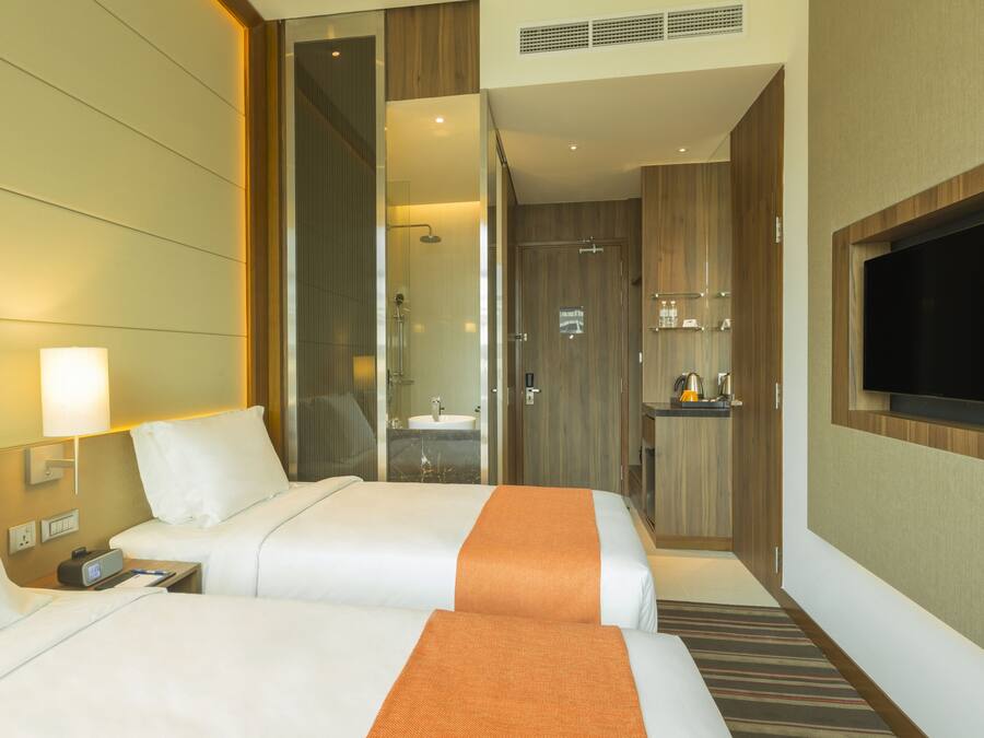 A hotel room with two beds, a TV, a bathroom, and a minibar.