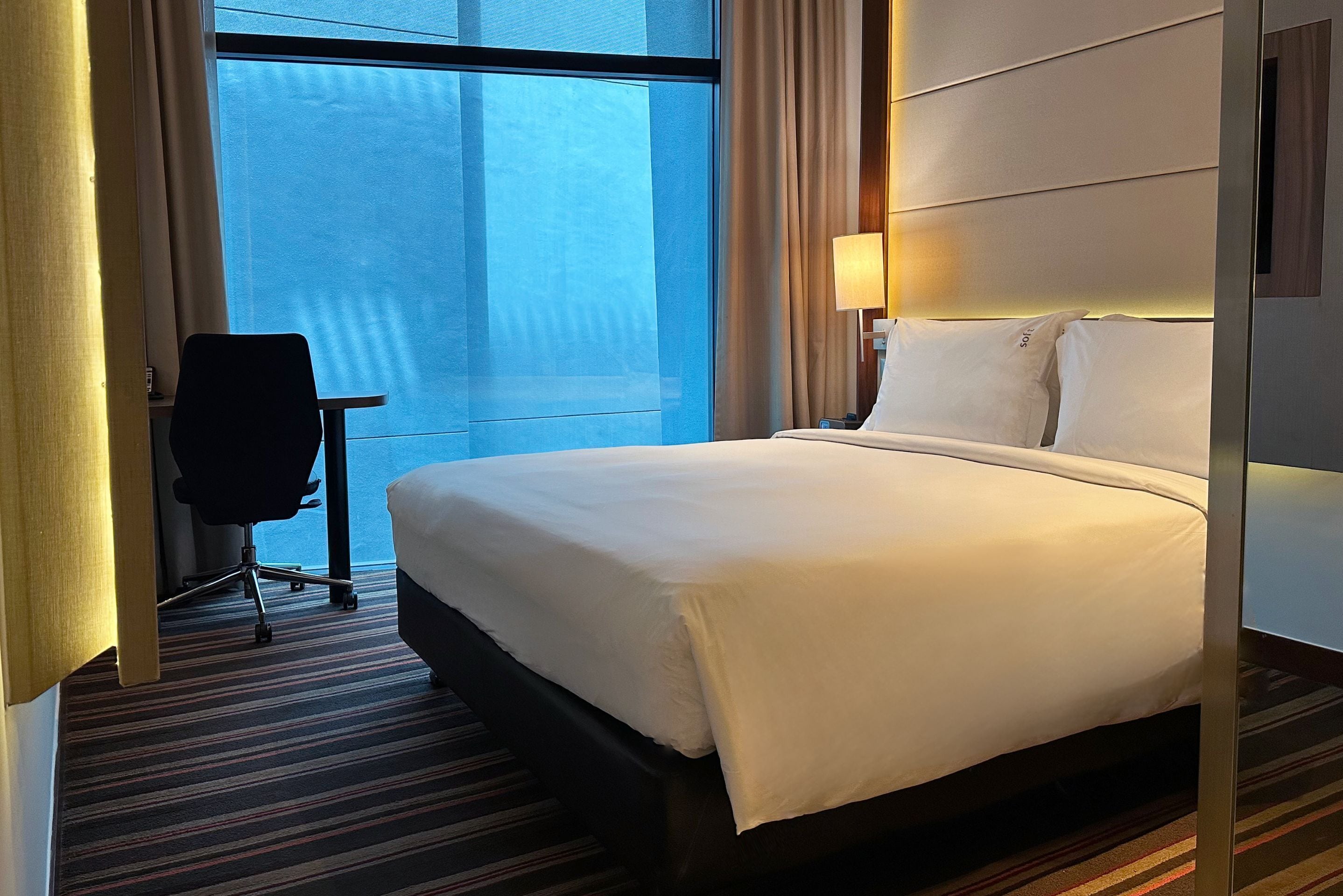 A hotel room with a large bed, a desk, and a chair.