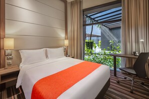 A hotel room with a bed, bedside lamps, a desk with a chair, and a view of greenery through a window. - Holiday Inn Express Singapore Clarke Quay by IHG (Singapore)