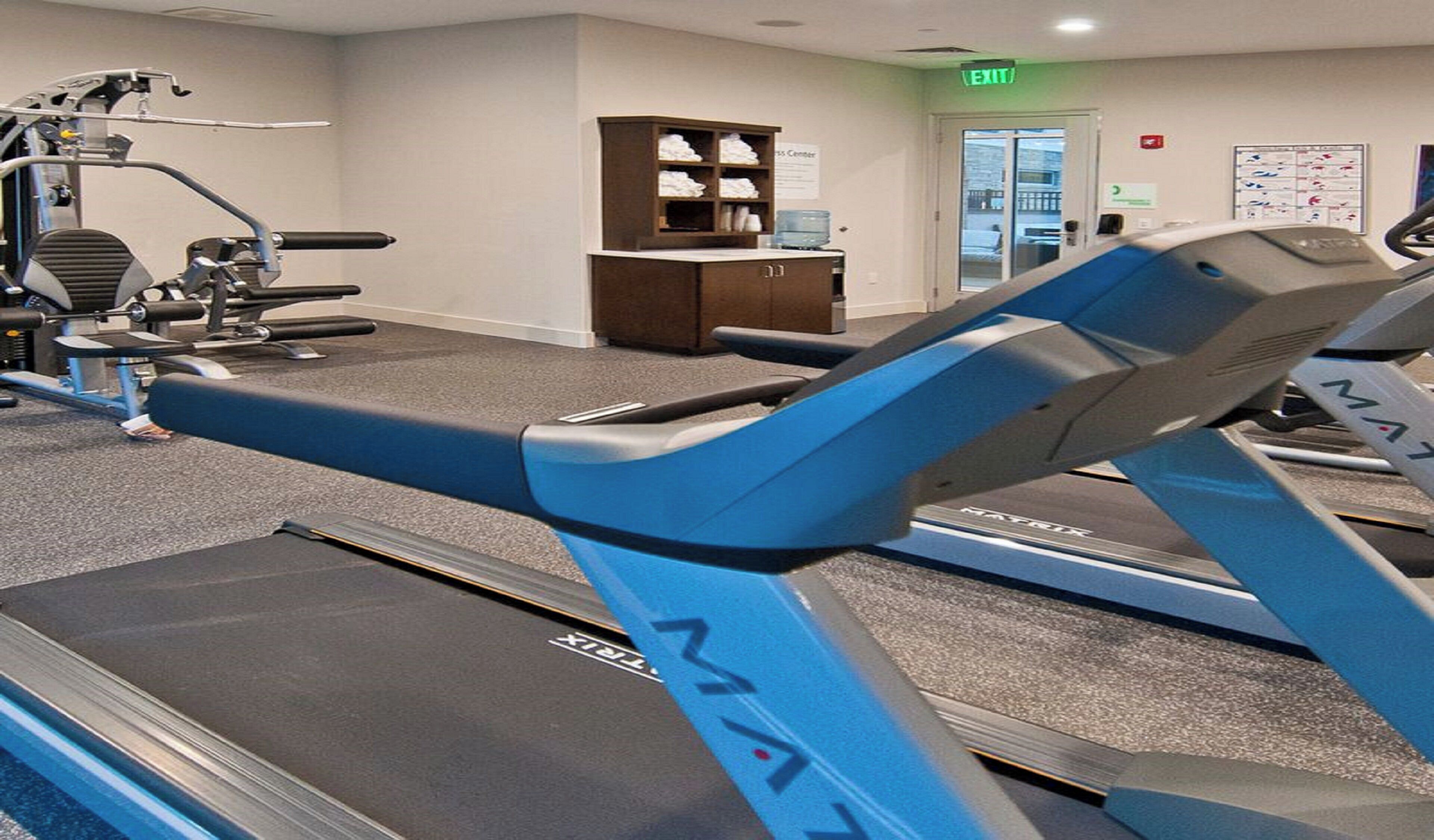 A gym with treadmills, weight machines, and a water dispenser.
