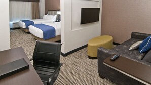 A hotel room with two beds, a TV mounted on the wall, a sofa, a small table, and a chair. - Holiday Inn Austin Airport by IHG (Austin)
