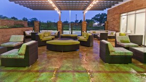 An outdoor patio area with wicker furniture and a covered seating area. - Holiday Inn Austin Airport by IHG (Austin)