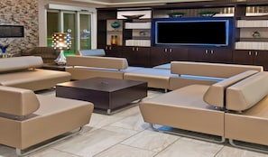A modern living room with a sofa set, a coffee table, and a flat-screen TV mounted on the wall. - Holiday Inn Austin Airport by IHG (Austin)