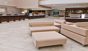 A spacious lobby with a reception desk, seating area, and a Starbucks coffee station. - Holiday Inn Austin Airport by IHG (Austin)