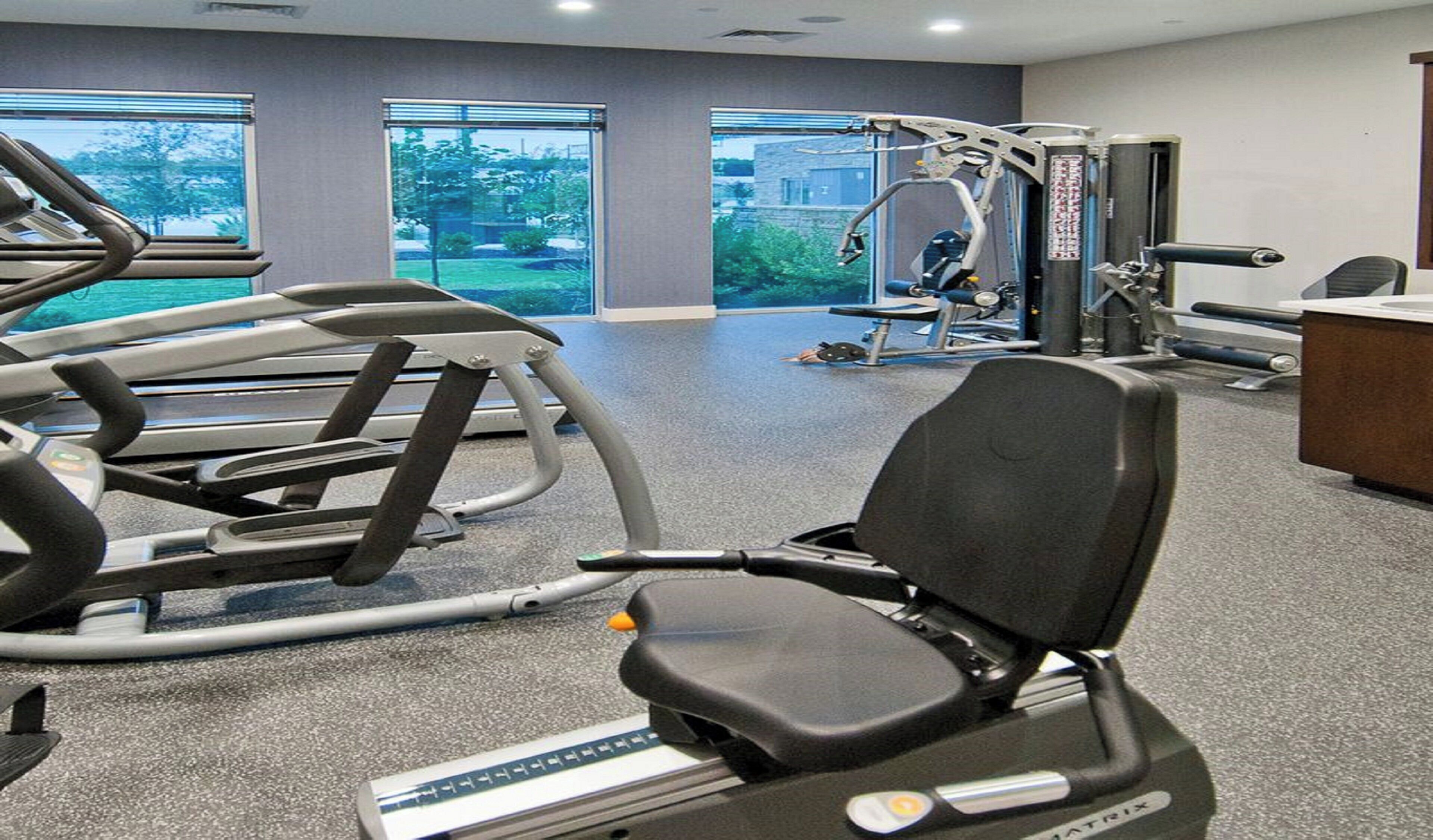 Un gimnasio con máquinas de cardio, pesas libres y una prensa de banca.
