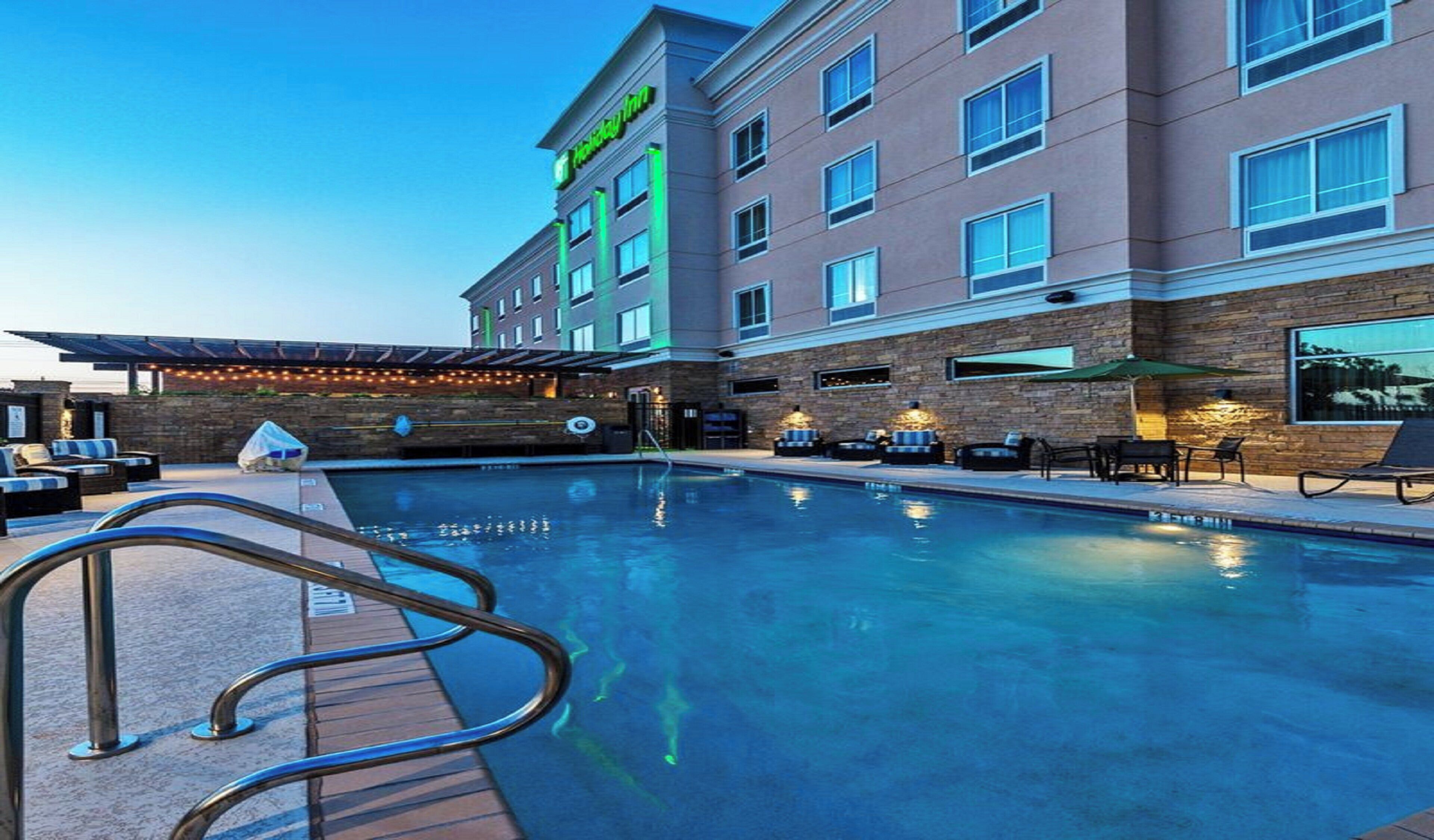 Un hotel con piscina, zona de estar exterior y patio cubierto.