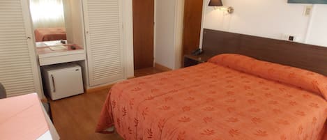 A bedroom with a bed, a desk, a wardrobe, and a nightstand.