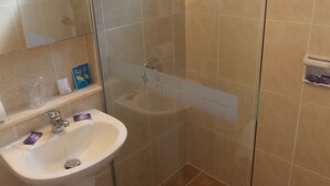 A bathroom with a white sink, a glass-enclosed shower, and beige tiles. - Bonne Etoile Hotel (Punta del Este)