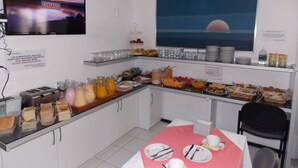 A breakfast buffet with various food items and beverages, a television displaying a sunset, and a sign prohibiting smoking. - Bonne Etoile Hotel (Punta del Este)