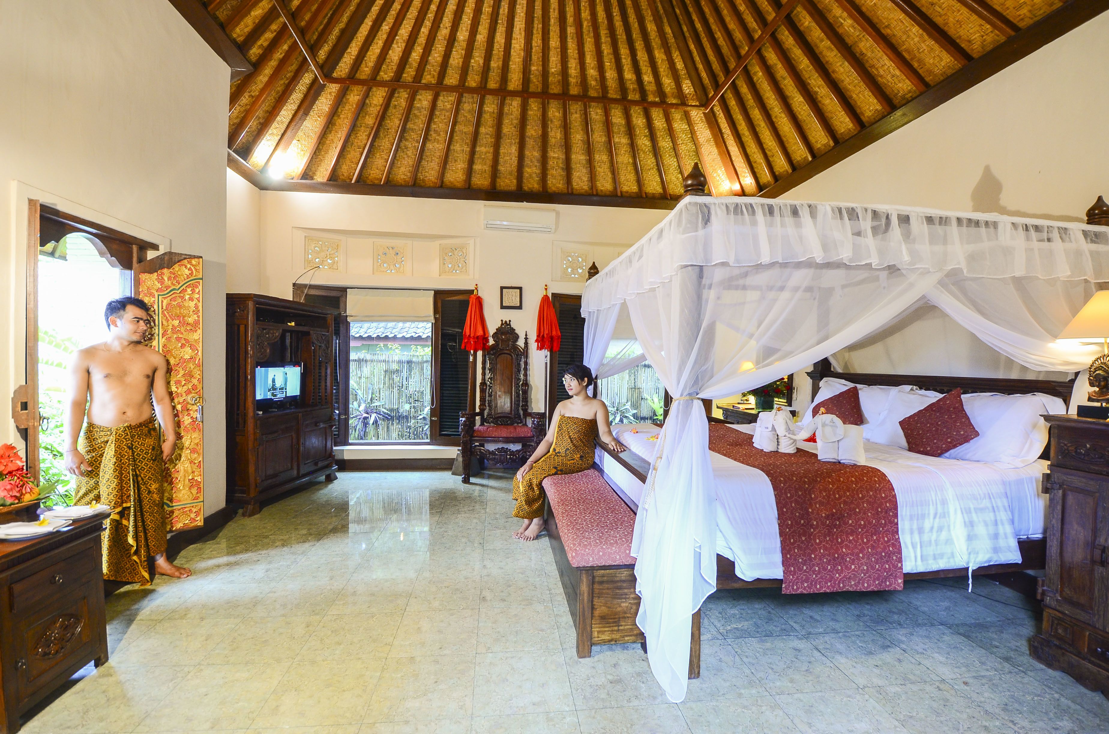 A room with a bed, a bench, a wooden cabinet, and a television.