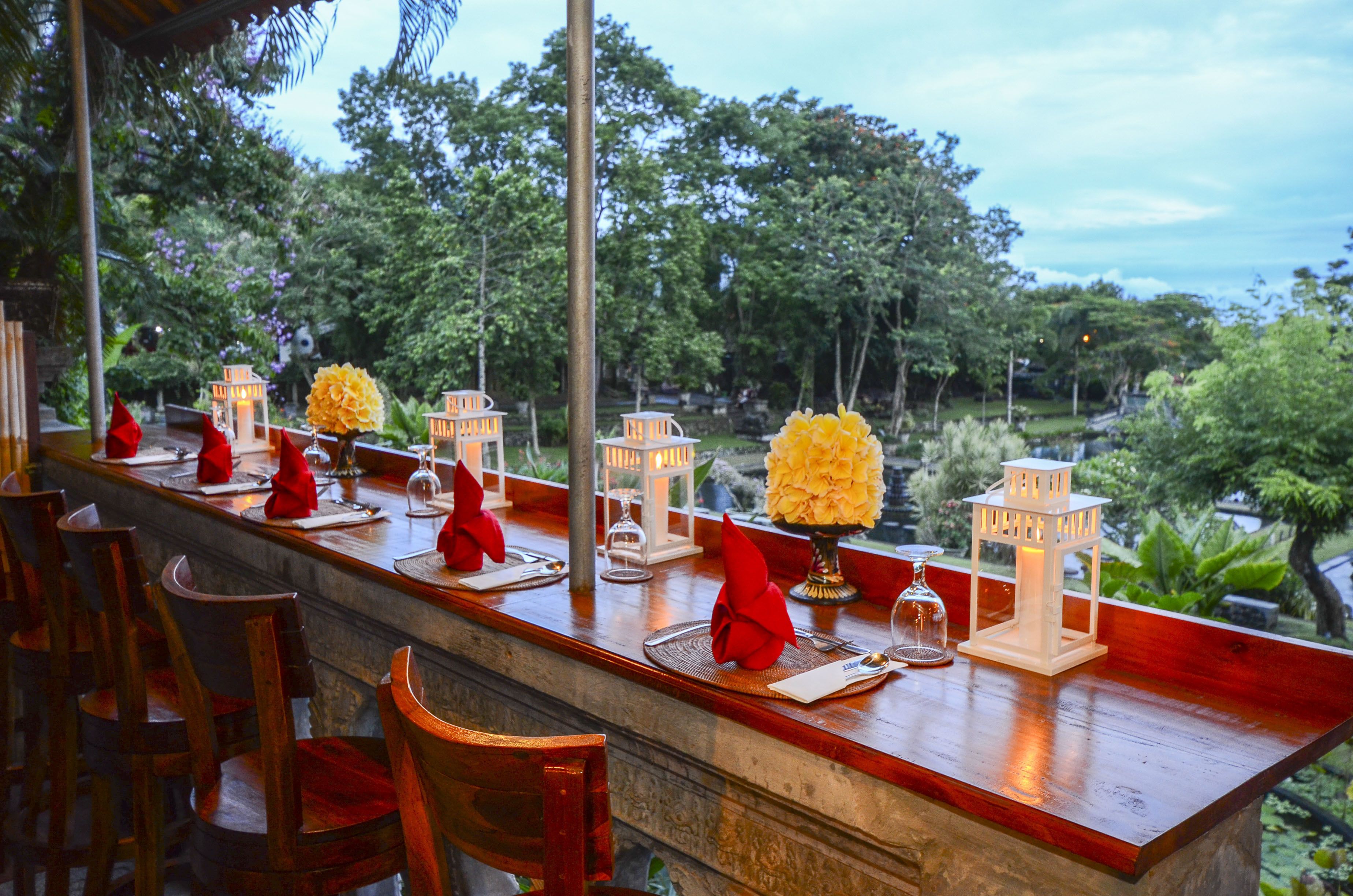 A restaurant with a long wooden counter, red napkins, and white lanterns.
