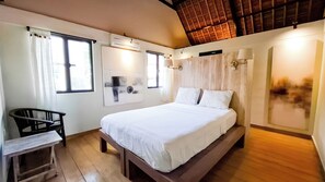 A bedroom with a bed, a chair, a window, and a wall-mounted air conditioner. - Villa Puri Darma Agung (Ubud)