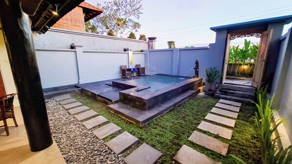 A backyard with a pool, stone steps, and a patio area.