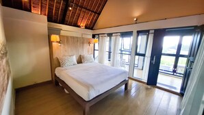 A bedroom with a large bed, wooden ceiling, and a view through a glass door. - Villa Puri Darma Agung (Ubud)