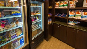 A refrigerated display case with various food items and a shelf stocked with bags of chips. - Capital Suites Yellowknife (Yellowknife)